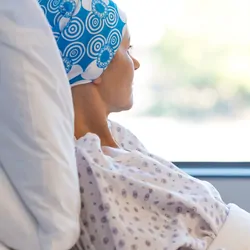 Cancer patient laying in hospital bed, looking out the window