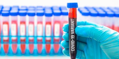 Gloved hand holding a vial of blood with the words "COVID-19 variant" written on it