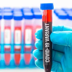 Gloved hand holding a vial of blood with the words "COVID-19 variant" written on it