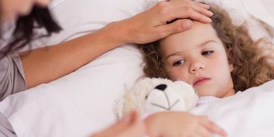 Young girl, sick in bed with mother checking her temperature