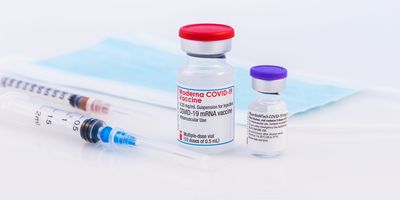 Vaccine vials next to two needles and face masks