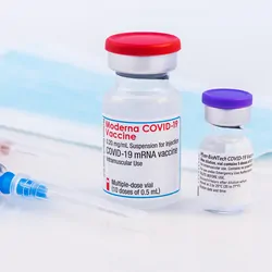 Vaccine vials next to two needles and face masks