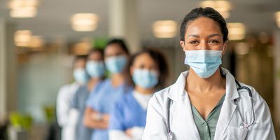 Health care profesionals wearing masks and facing the camera looking determined