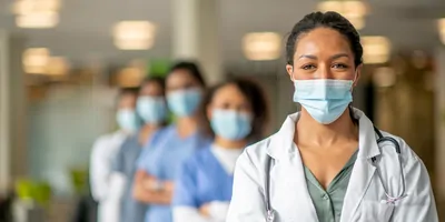 Health care profesionals wearing masks and facing the camera looking determined