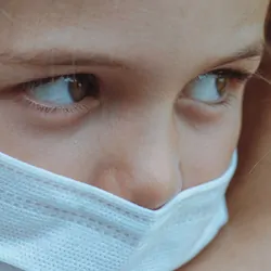 Young girl wearing face mask held in mothers arms