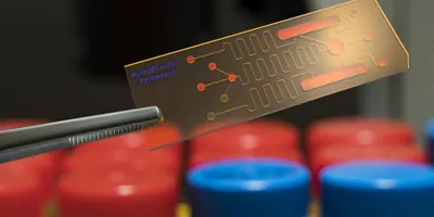 microfluidic processor, lab on chip, being held by tweezers
