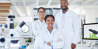 Photo of three clinical laboratory professionals wearing white lab coats.