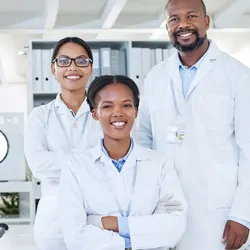 Photo of three clinical laboratory professionals wearing white lab coats.