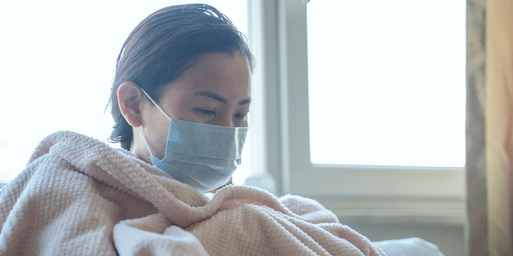 Sick women wearing a mask in a blanket