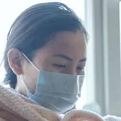 Sick women wearing a mask in a blanket