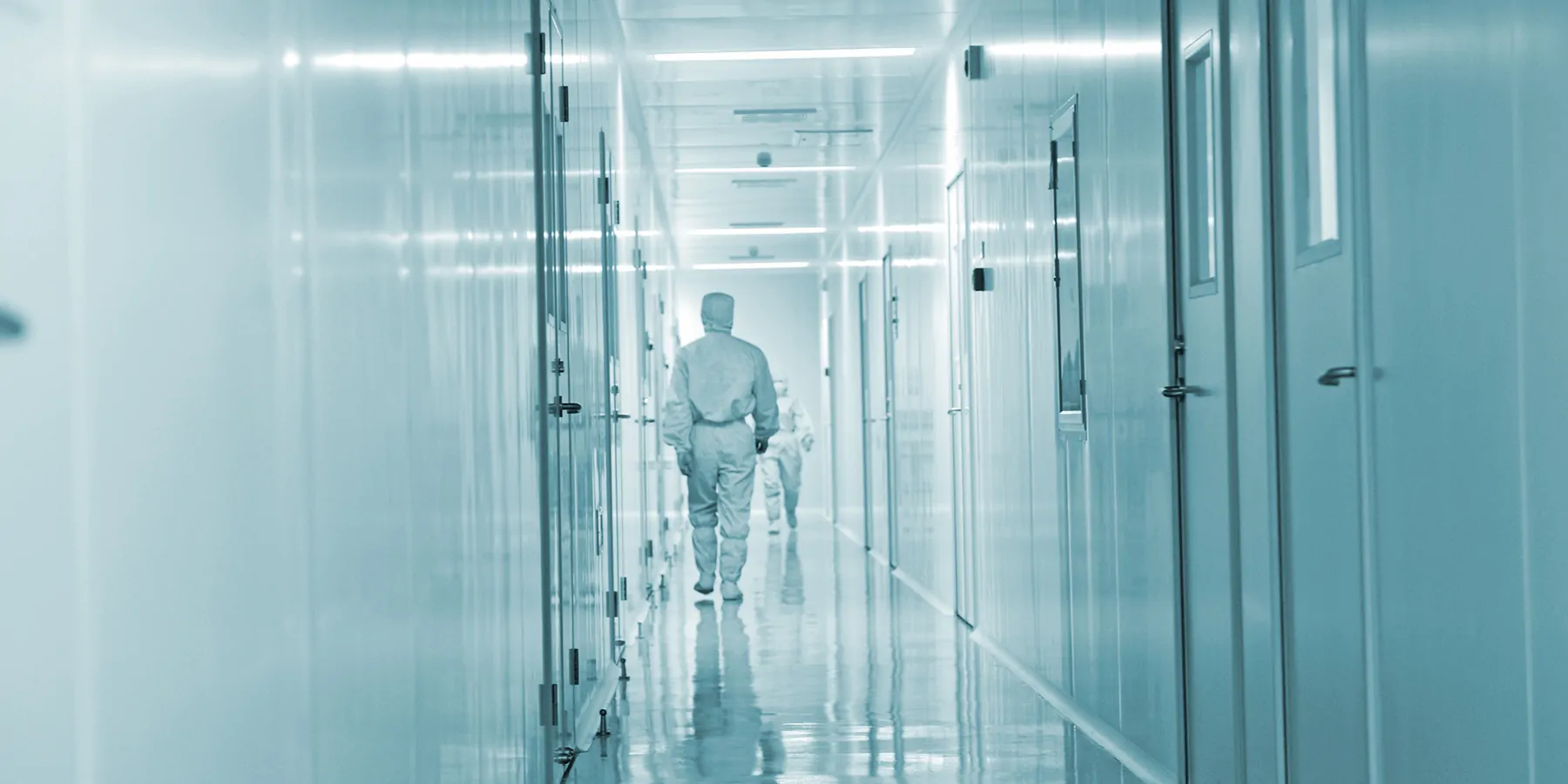 Clinical biobank professionals wearing PPE walking down a hall in the specimen biobank.