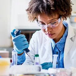 Photograph of a clinical lab professional using a well calibrated pipette for liquid handling in her experiments.