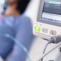 Woman in hospital bed with oxgen machine in the fore ground