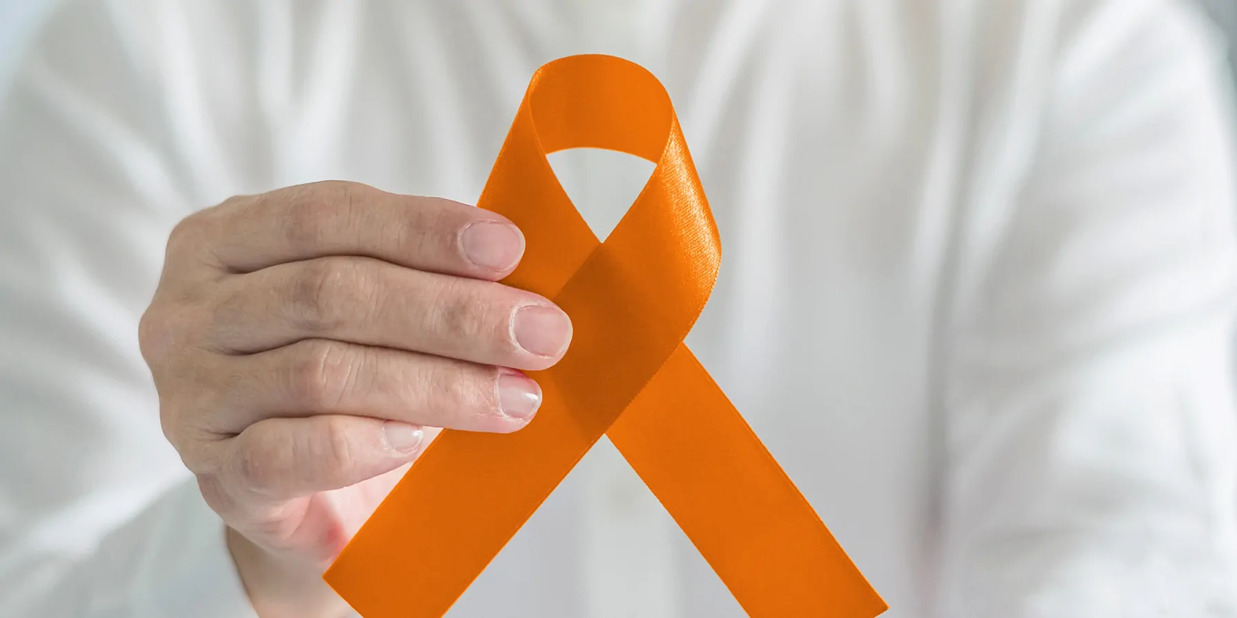 Does Multiple Sclerosis Play a Role in Cancer Screening and Diagnosis? Person holding an orange ribbon