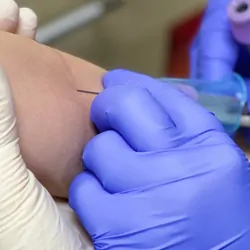 Health care professional drawing blood from the arm of a young patient