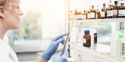 Photograph of a clinical researcher using a smart device to access the lab’s chemical inventory during her .experiment