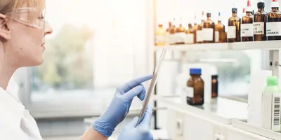 Photograph of a clinical researcher using a smart device to access the lab’s chemical inventory during her .experiment