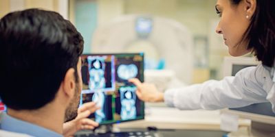 Medical professionals discuss the results of a radiotheranostics CT scan for a person with cancer.