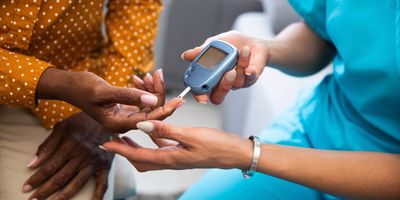 Female health care provider takes blood glucose sample of a Black patient