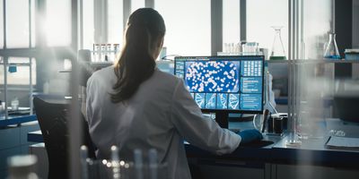 Photo of a clinical lab professional sitting at a computer designing a precision medicine lab.