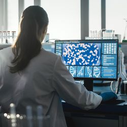 Photo of a clinical lab professional sitting at a computer designing a precision medicine lab.