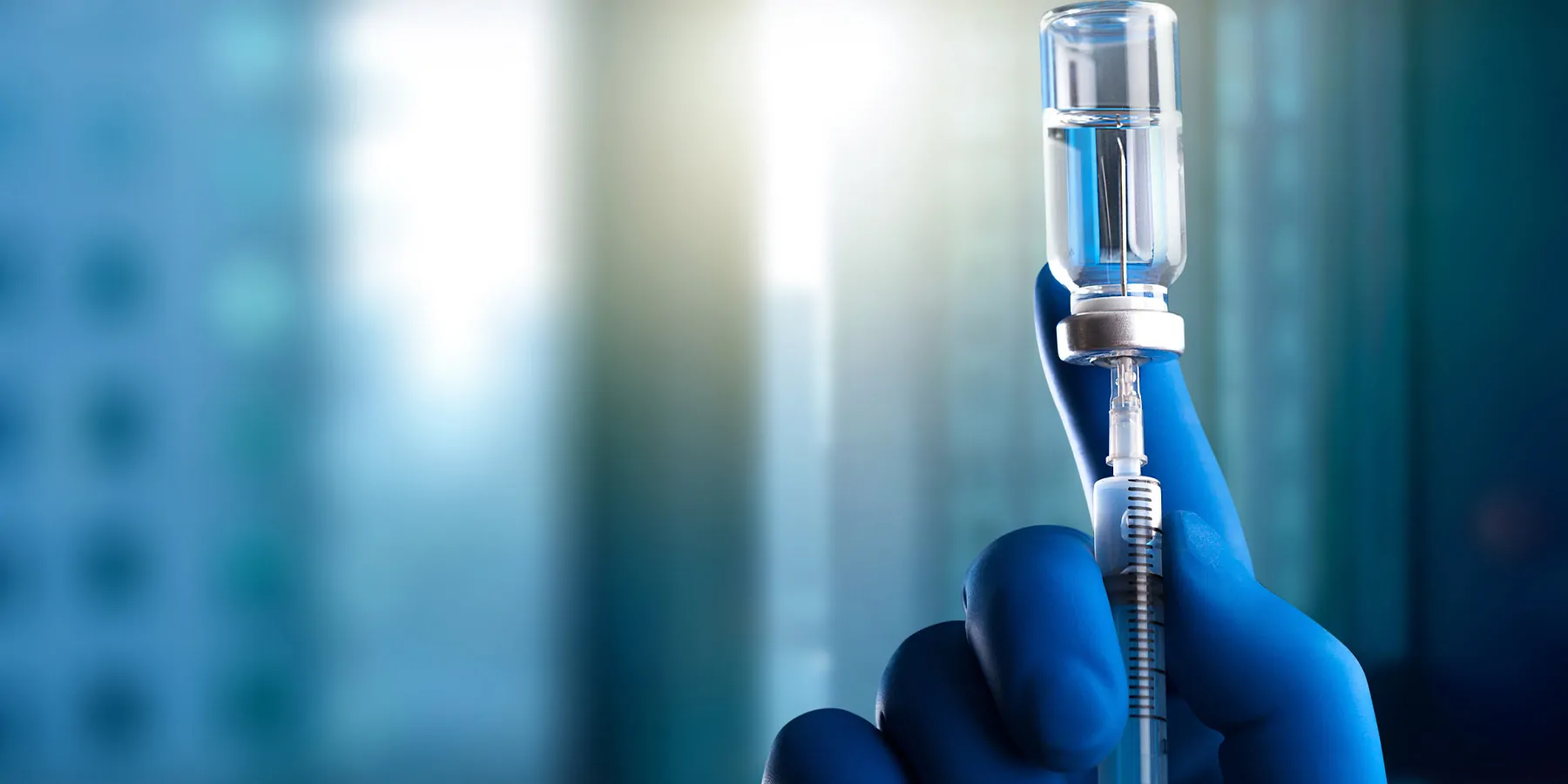 Gloved hand drawing medication into a syringe