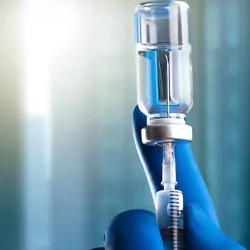Gloved hand drawing medication into a syringe
