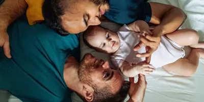 Photograph of a couple with their baby happily spending time together as an outcome of preventing Sudden Infant Death Syndrome (SIDS).