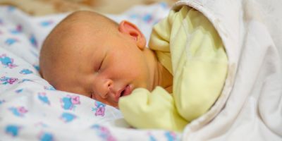 A newborn baby with jaundice, sleeping in a crib