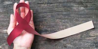 Hand holding a ribbon for oral cancer