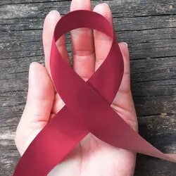 Hand holding a ribbon for oral cancer