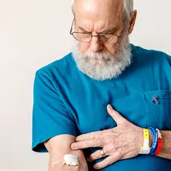 Older gentleman, cancer survivor showing arm where he got a blood test