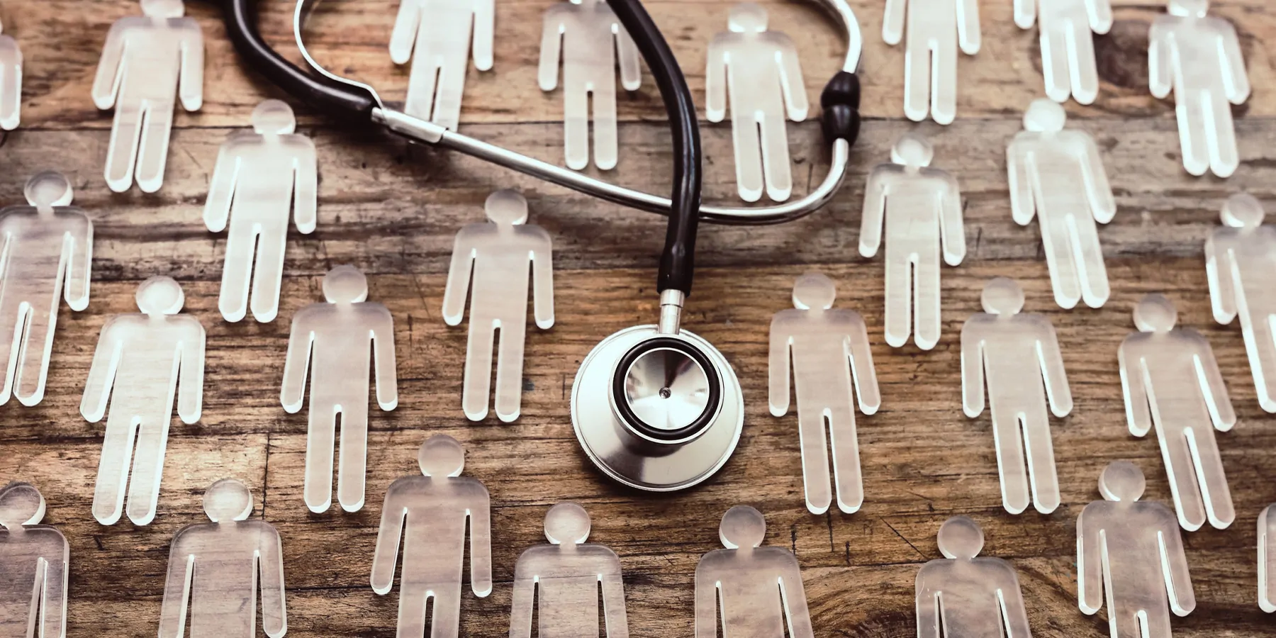 Glass figures of men on a wooden table with a stethoscope