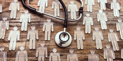 Glass figures of men on a wooden table with a stethoscope