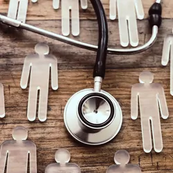Glass figures of men on a wooden table with a stethoscope