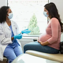 A doctor talks to a pregnant patient about non-invasive pregnancy screening tests.