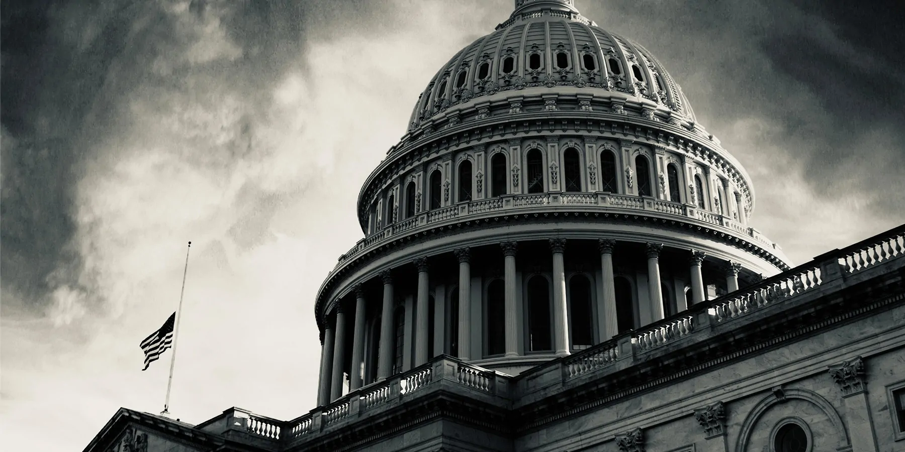 Those Who Seek to Harm Health Care Workers Could Face Extra Penalties Photo of the US Capitol Building in greyscale with ominous clouds.