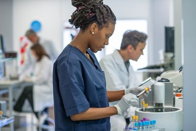 Photograph of clinical lab personnel working alongside automation in a clinical lab.