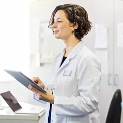 A clinical lab professional holding a tablet with an easily-generated, comprehensive, and clinically interpretable report of NGS data for a patient with rare cancer.