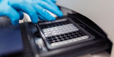 Photo of a clinical lab professional loading an mRNA plate into automation platform.