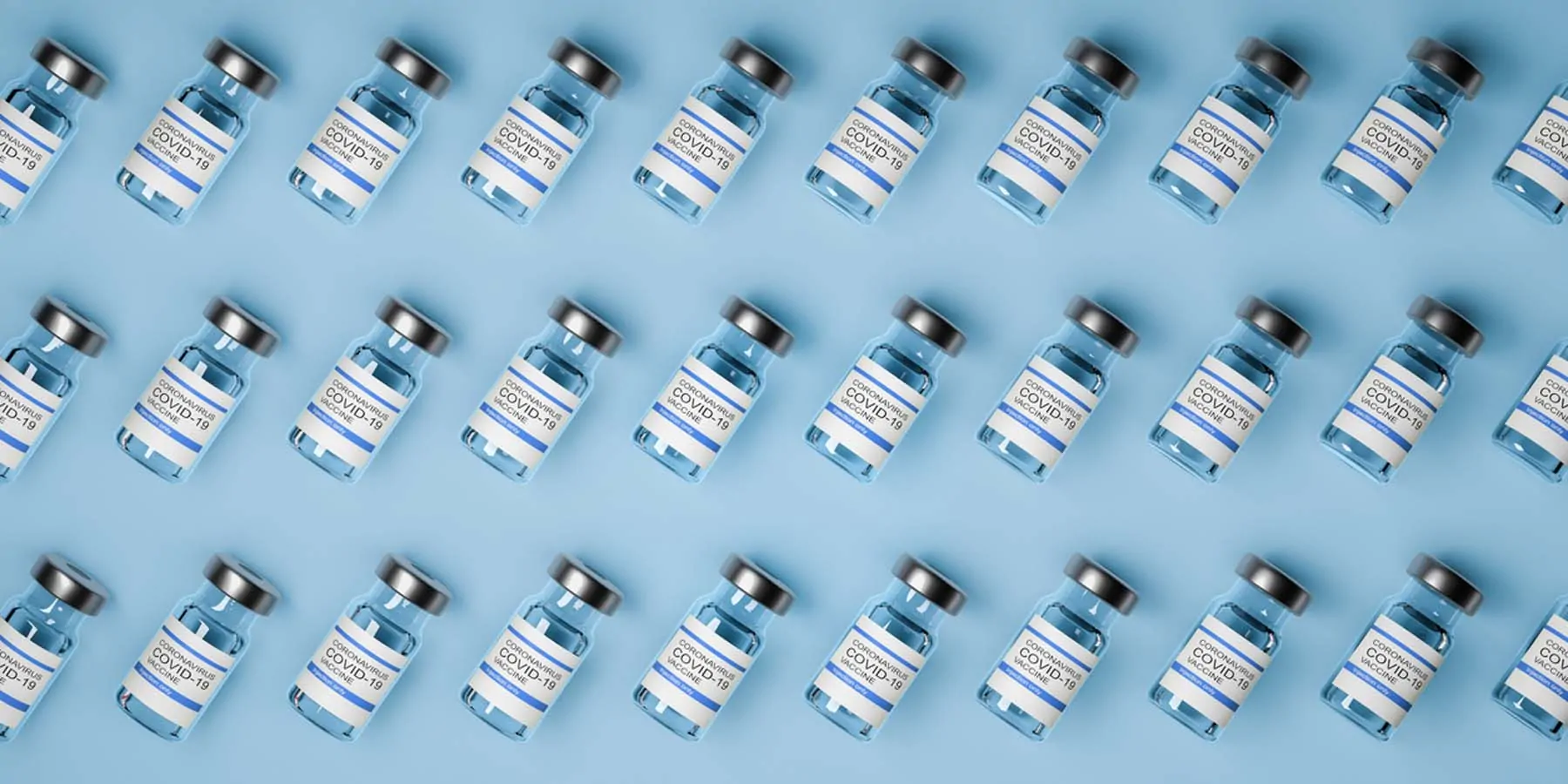 Photo of glass vials of COVID-19 vaccines against a blue background.