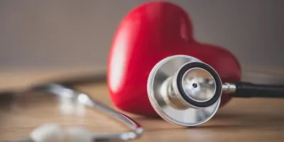Plastic heart next to a stethoscope on a table