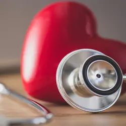 Plastic heart next to a stethoscope on a table