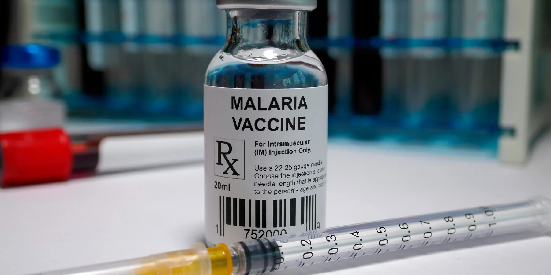 Malaria vaccine bottle with needle on table