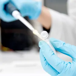 Lab tech wearing gloves and pipetting 