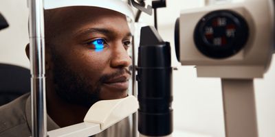 Young man getting his eye’s examined with a slit lamp