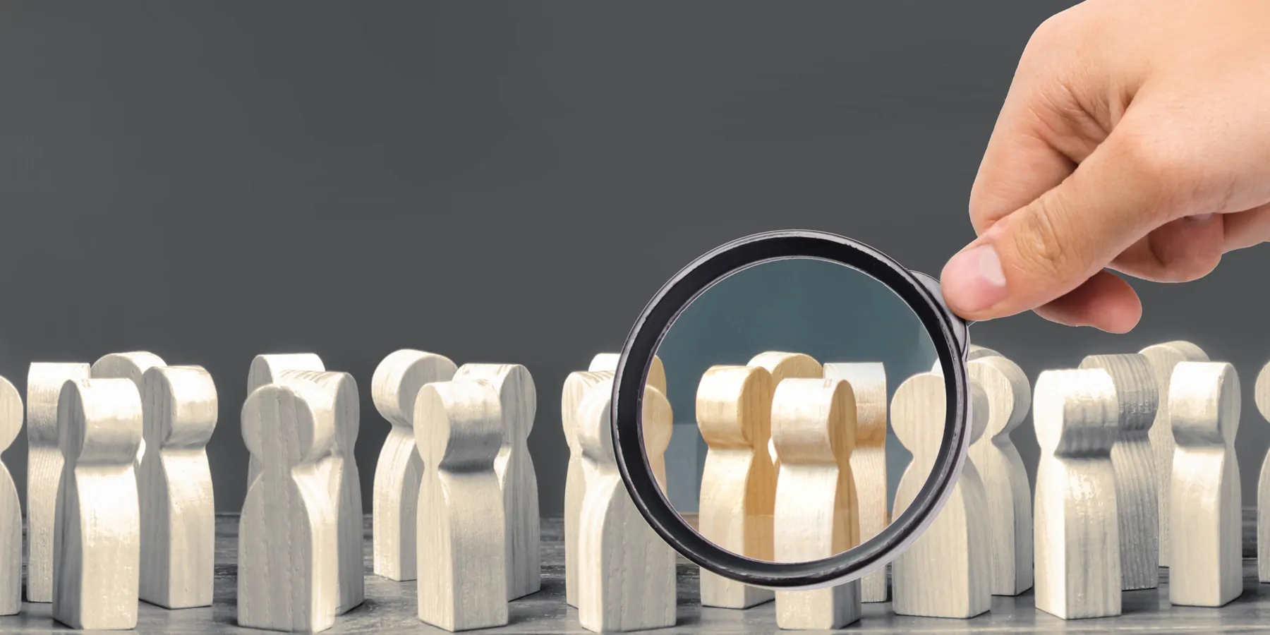 A magnifying glass looks at a crowd of wooden figures