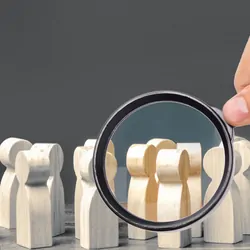 A magnifying glass looks at a crowd of wooden figures