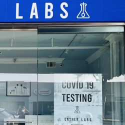 Photo of the Gather Labs storefront with a sign in the window advertising COVID-19 diagnostic testing.