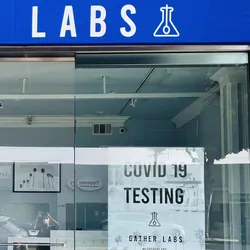 Photo of the Gather Labs storefront with a sign in the window advertising COVID-19 diagnostic testing.
